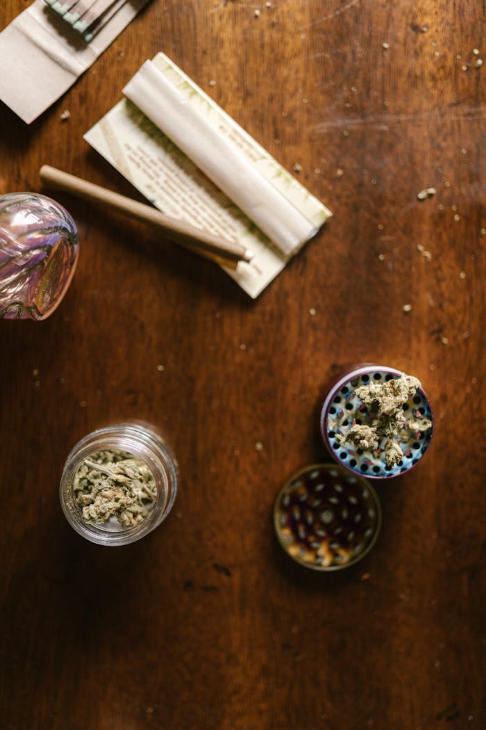 The Art of Drawing Readers In: Your attractive post title goes here Glass jar, grinder, and joint papers on a wooden table, representing cannabis culture.