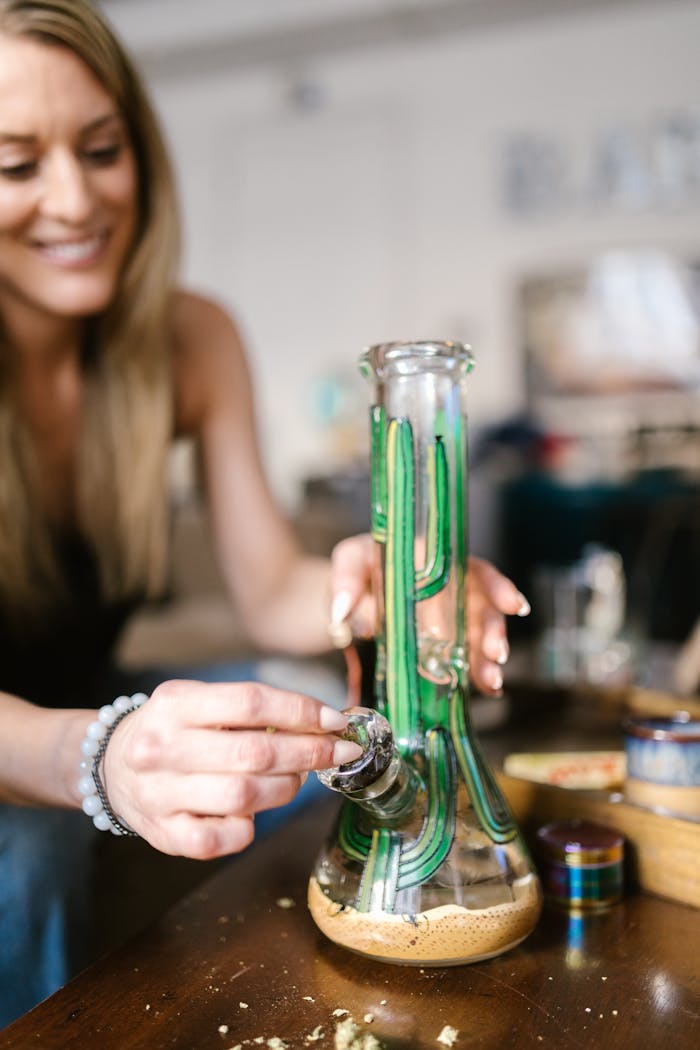 Mastering the First Impression: Your intriguing post title goes here Smiling woman handling a glass bong, highlighting lifestyle and cannabis culture indoors.